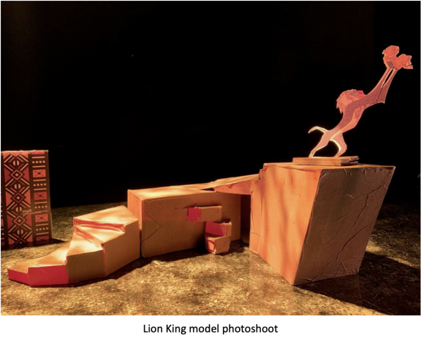 Stylized Lion King stage model photographed under warm theatrical lighting, featuring layered rocky platforms and a silhouetted figure of Rafiki holding Simba aloft atop Pride Rock. Caption at the bottom reads: ‘Lion King model photoshoot.